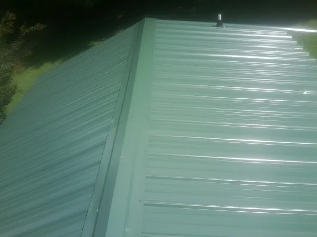 New green metal panels meeting at the ridge of a roof — Flat Roof Repair work by our crew in Brookfield