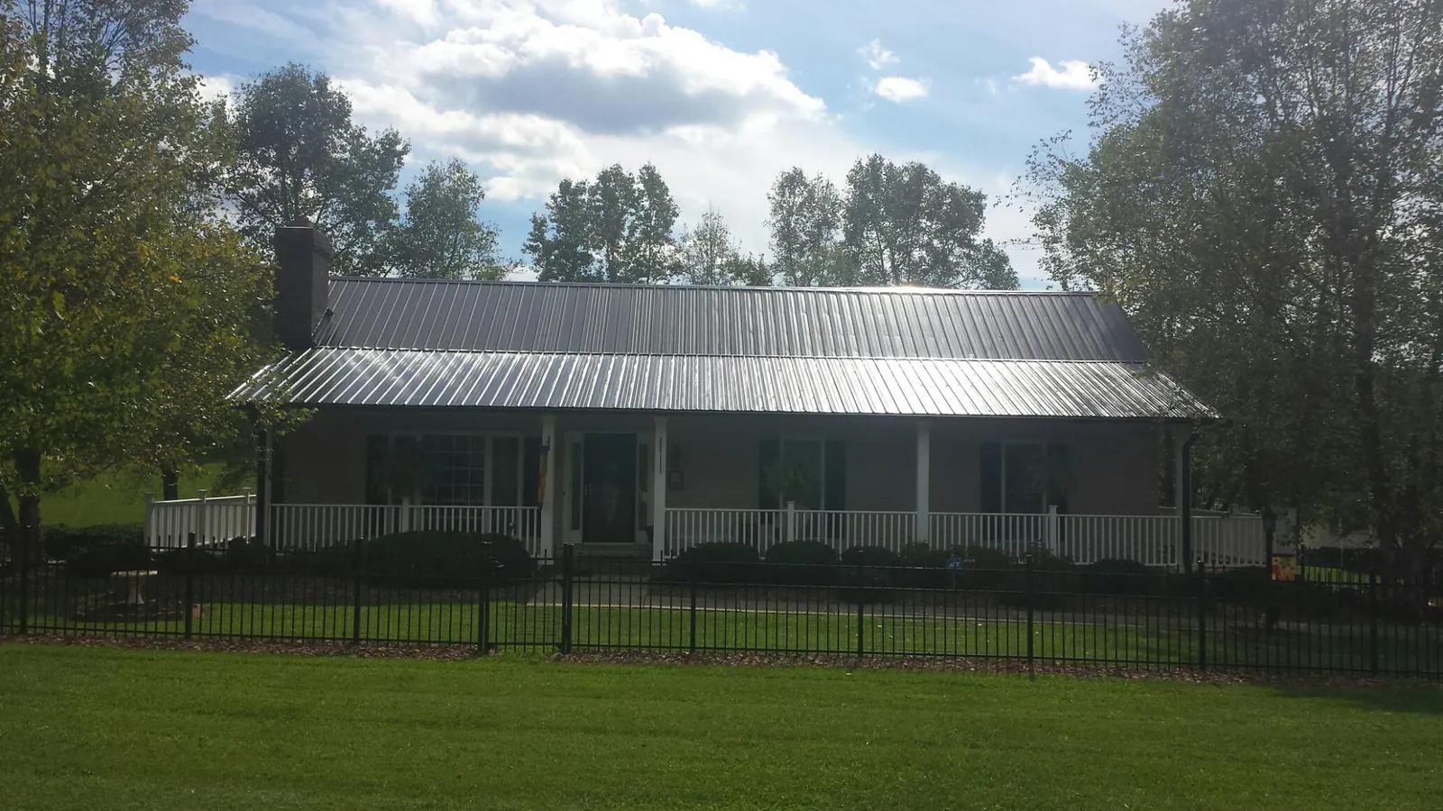 Gray metal roof on a brick ranch with a full width front porch — Gutter Guard Installation work by our crew in Brookfield